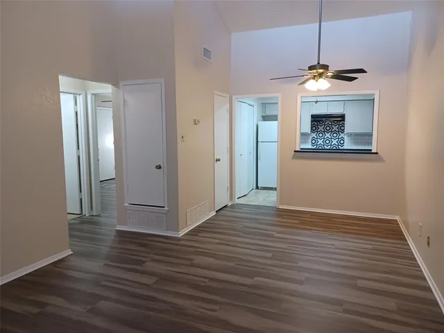 a view of an empty room with wooden floor and a chandelier