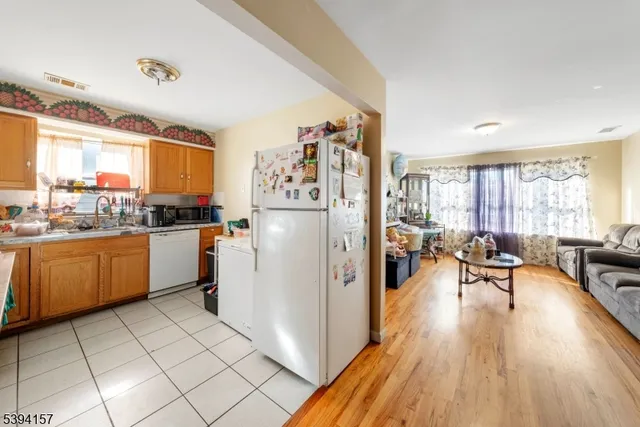 a kitchen with a refrigerator a stove a sink dishwasher and a dining table with wooden floor