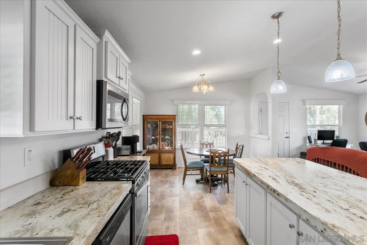 9100 Single Oak Drive Lakeside, CA 92040 - Photo 16 of 28 a large kitchen with kitchen island granite countertop a stove a sink a dining table and chairs with wooden floor