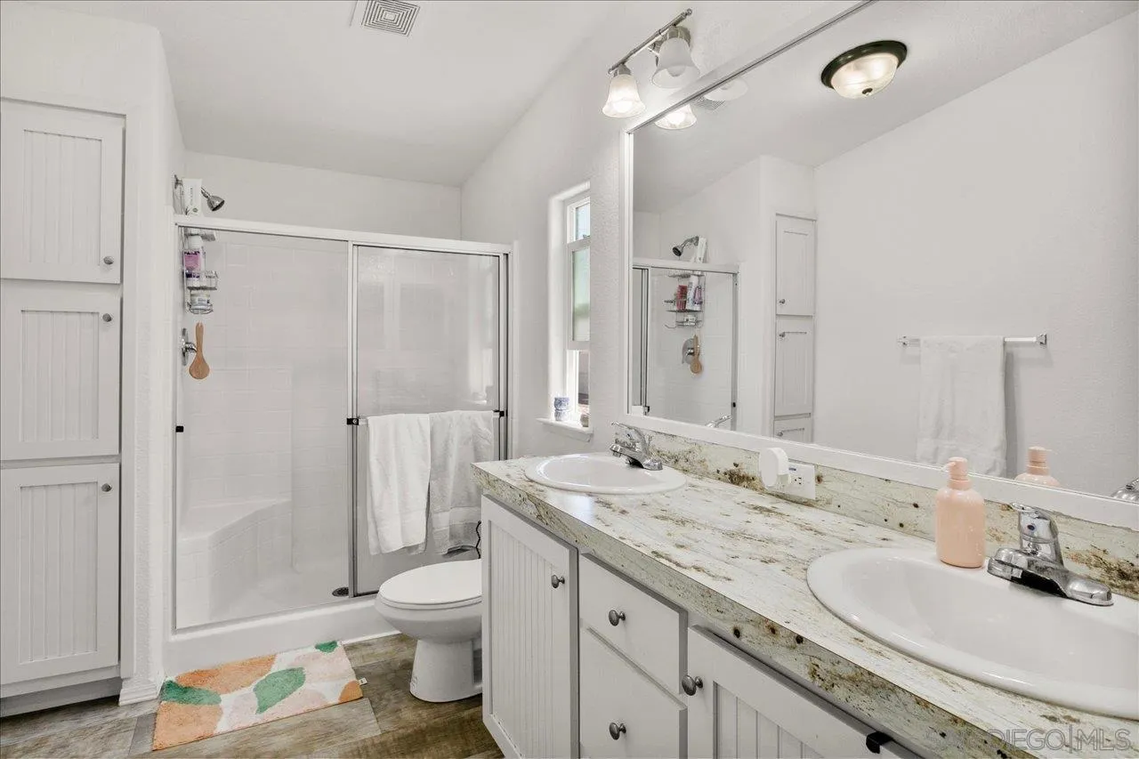 9100 Single Oak Drive Lakeside, CA 92040 - Photo 21 of 28 a bathroom with a granite countertop sink toilet a large mirror and shower