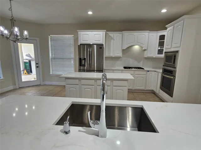 a view of a kitchen with granite countertop a sink a window stainless steel appliances and cabinets