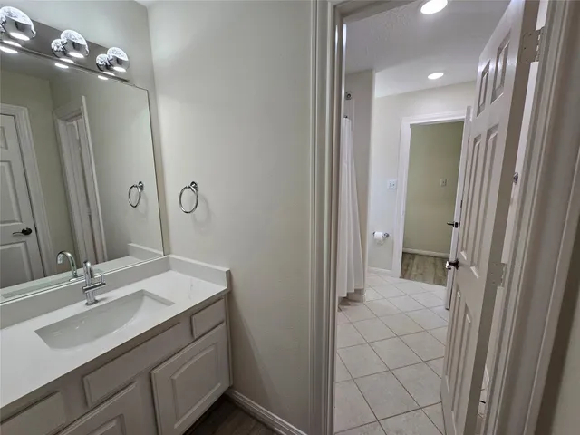 a view of an empty room with wooden floor and a fan