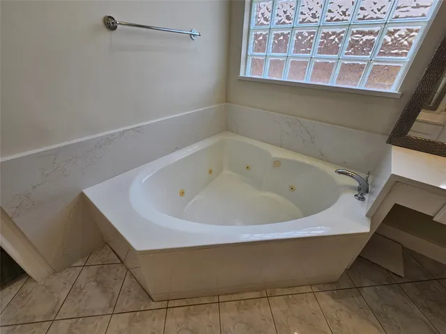 a spacious bathroom with a bathtub sink and mirror