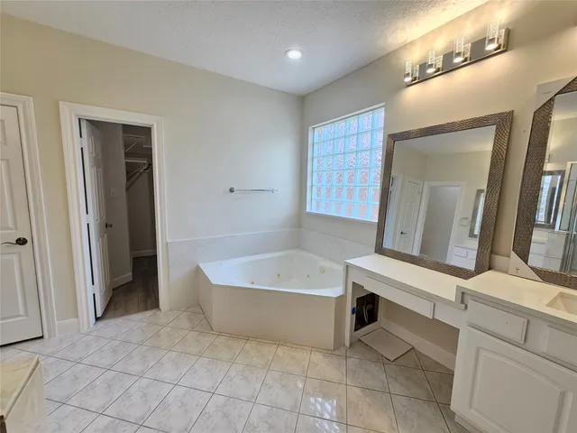 a bathroom with a tub a sink a mirror and a shower