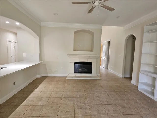 a view of a livingroom with a fireplace a ceiling fan and windows