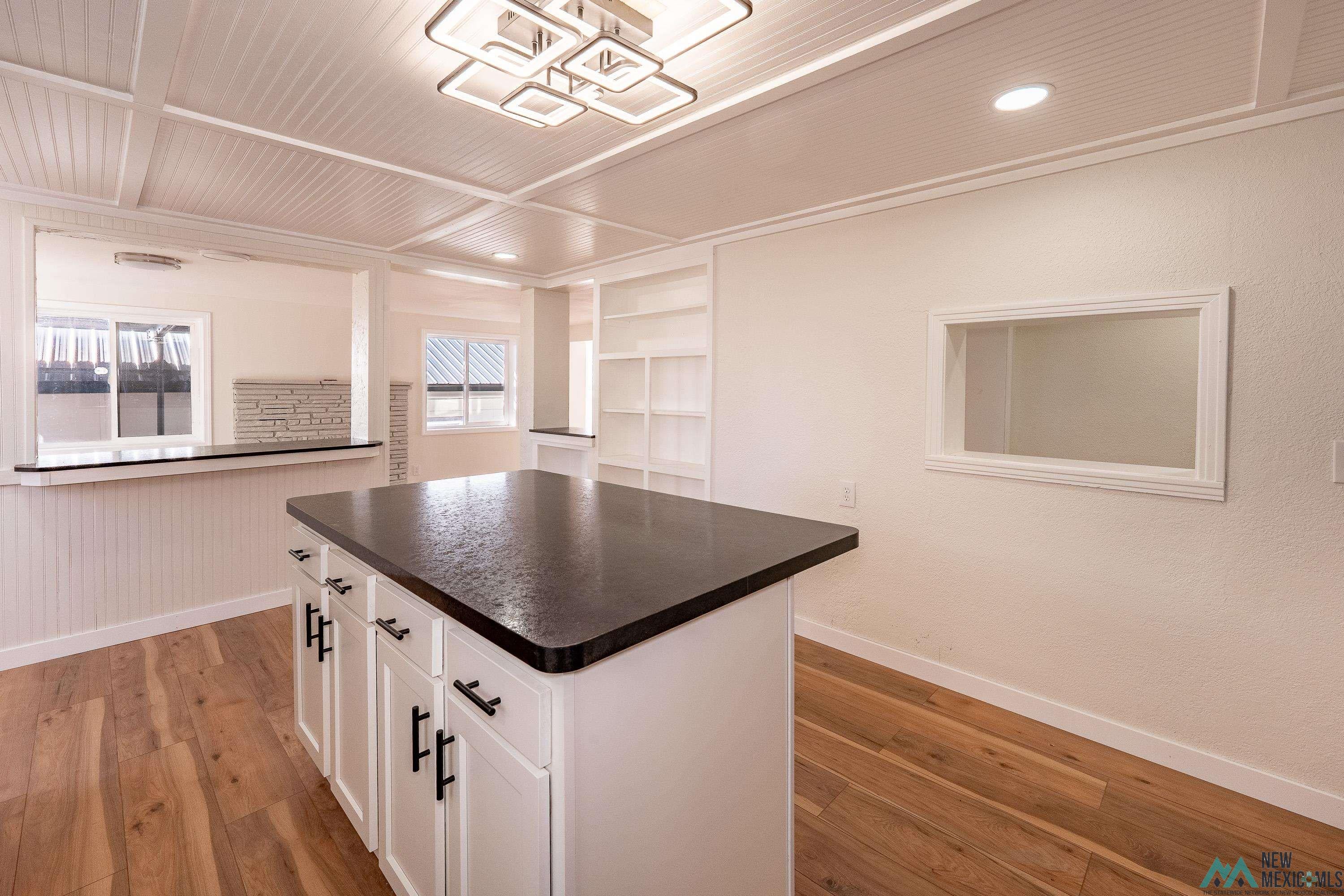 1131 Lincoln Avenue Raton, NM 87740 - Photo 6 of 41 Kitchen with white cabinets, dark countertops, light wood finished floors, a center island, and built in shelves