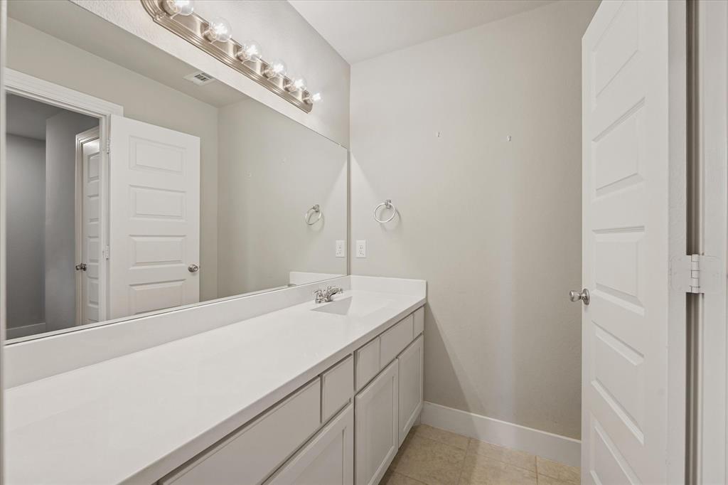 2044 Longbridge Road Forney, TX 75126 - Photo 26 of 40 Long vanity with a white countertop and integrated sink, under-cabinet storage, and a large wall-mounted mirror