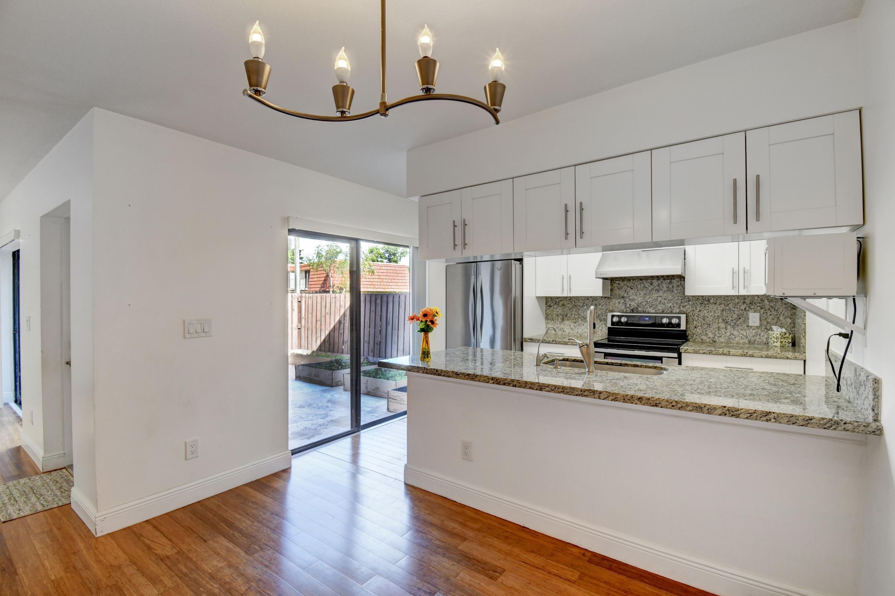 8253 Boca Rio Drive Boca Raton, FL 33433 - Photo 3 of 15 a kitchen with stainless steel appliances granite countertop a refrigerator a sink dishwasher a stove and white countertops with wooden floor