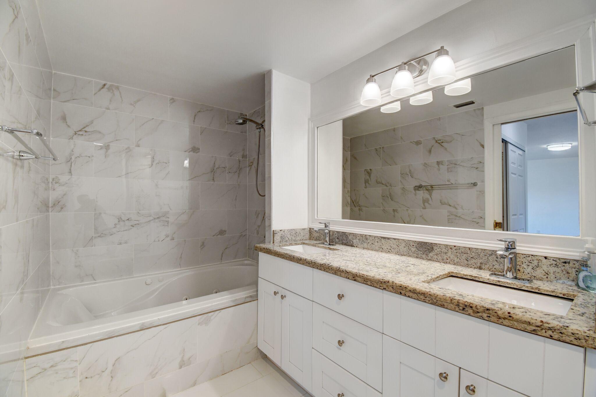 8253 Boca Rio Drive Boca Raton, FL 33433 - Photo 10 of 15 a bathroom with a granite countertop bathtub a sink and mirror
