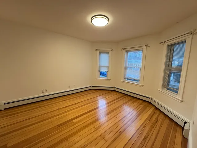a view of an empty room with window and wooden floor