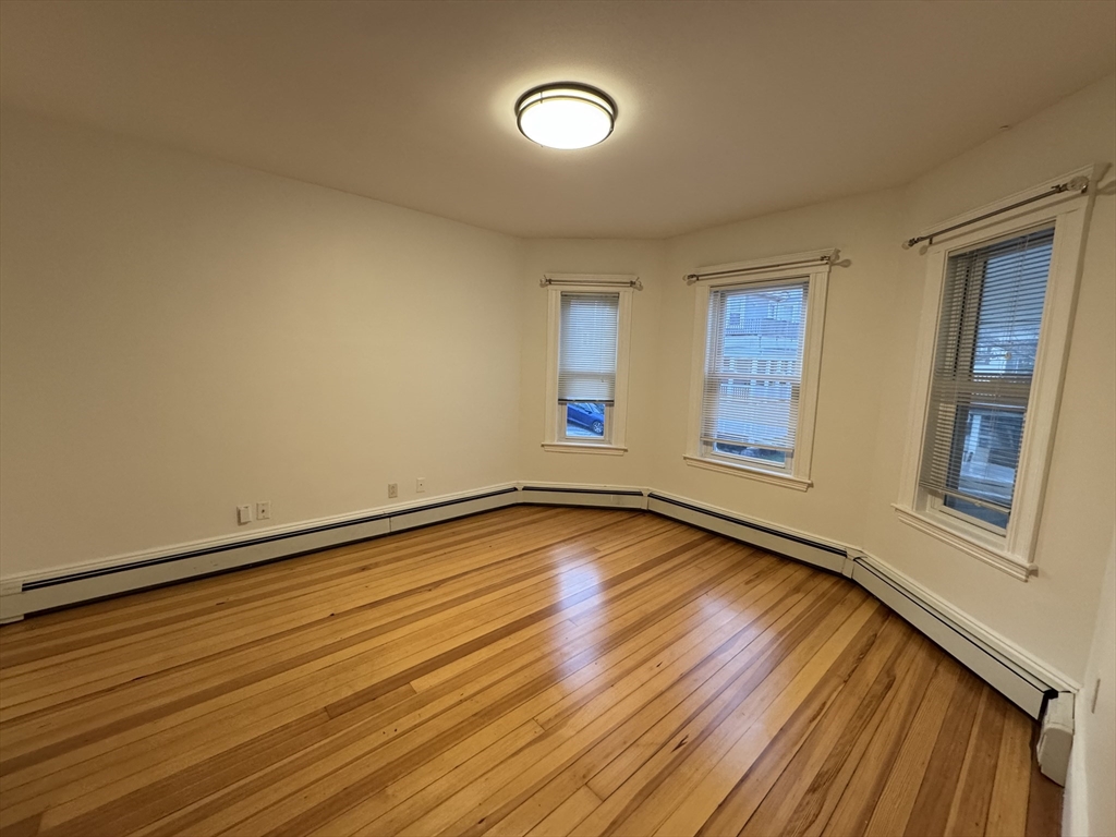 68 Aldrich Street, Unit 2 Boston, MA 02131 - Photo 2 of 12 a view of an empty room with window and wooden floor