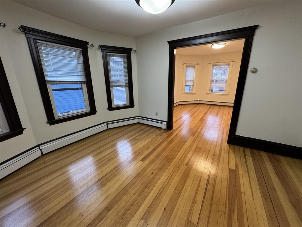 68 Aldrich Street, Unit 2 Boston, MA 02131 - Photo 3 of 12 a view of an empty room with wooden floor and a window