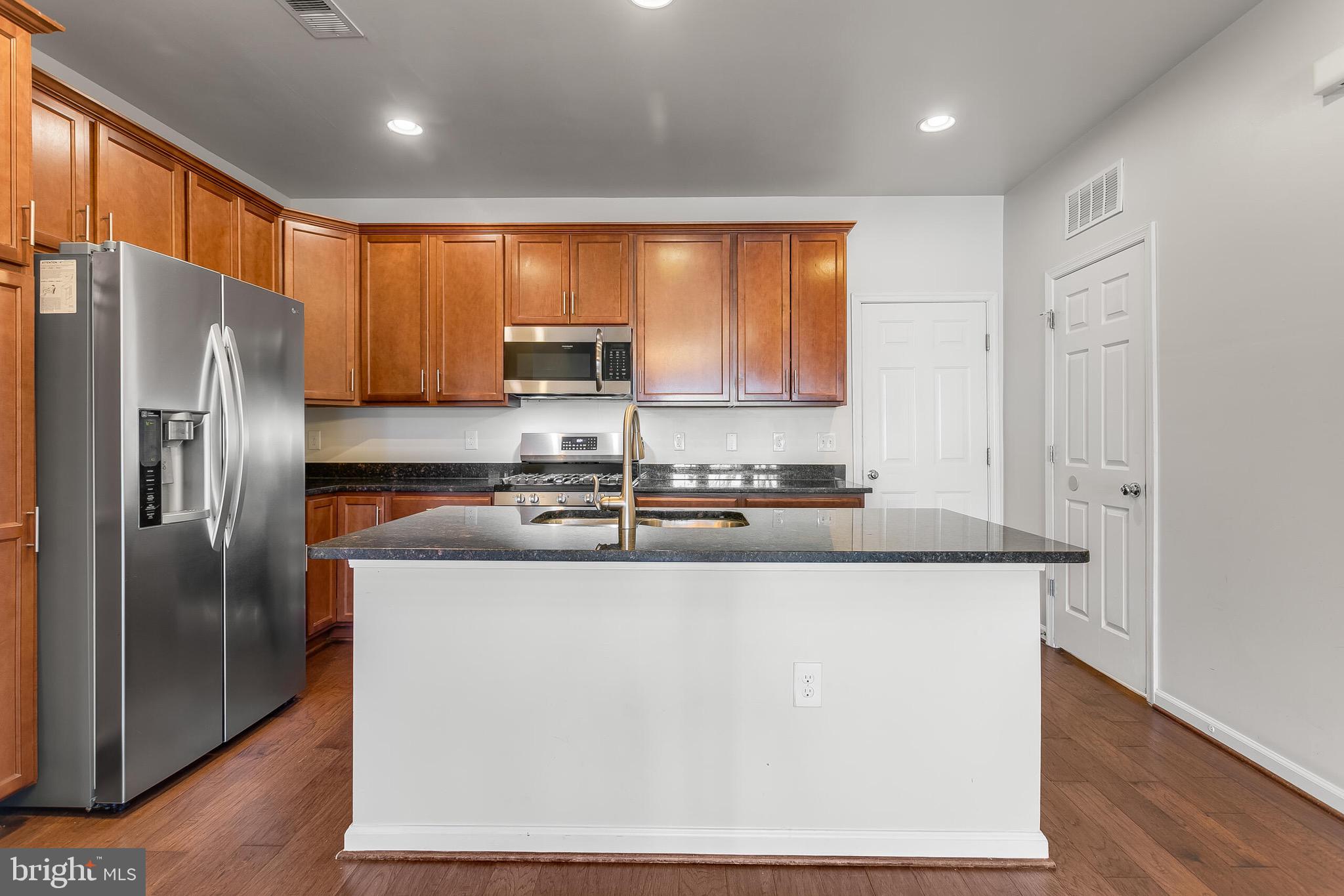 20586 Maitland Terrace Ashburn, VA 20147 - Photo 2 of 24 a kitchen with stainless steel appliances granite countertop a refrigerator a stove and a sink with wooden floor