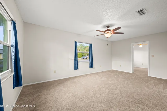 an empty room with windows and ceiling fan