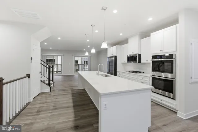 a large white kitchen with lots of counter space a sink appliances and cabinets