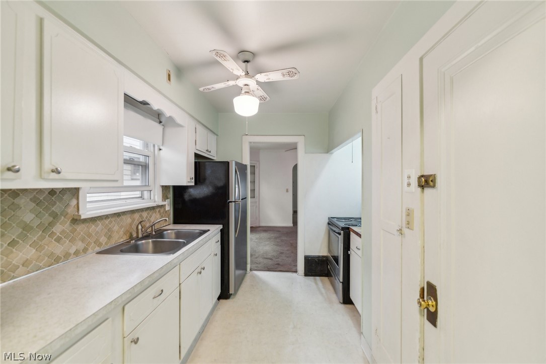 3619 Strathavon Road Cleveland, OH 44120 - Photo 13 of 49 Kitchen featuring ceiling fan, tasteful backsplash, light colored carpet, sink, and white cabinetry