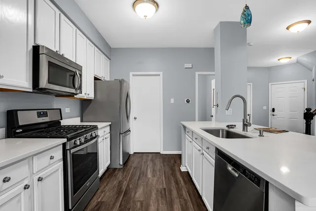 a kitchen with stainless steel appliances granite countertop a stove top oven a sink dishwasher and a refrigerator with wooden floor