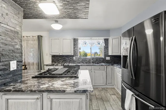 a kitchen with stainless steel appliances granite countertop a sink stove and refrigerator