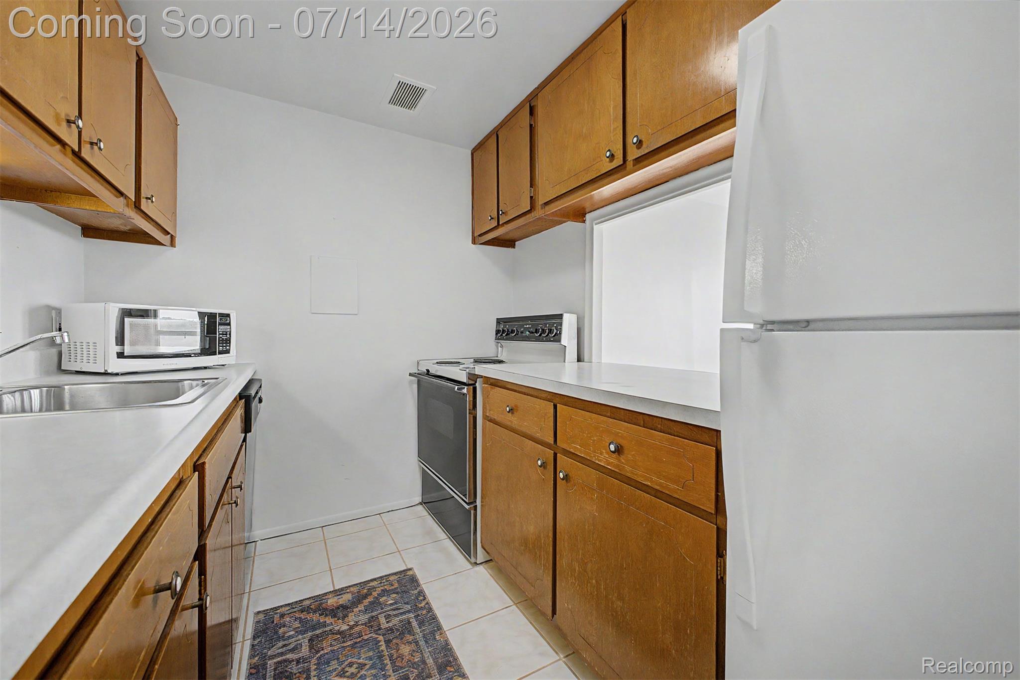 22700 Garrison Street, Unit 707 Dearborn, MI 48124 - Photo 9 of 22 Galley kitchen featuring wood-finish cabinetry, white countertops, and tile flooring