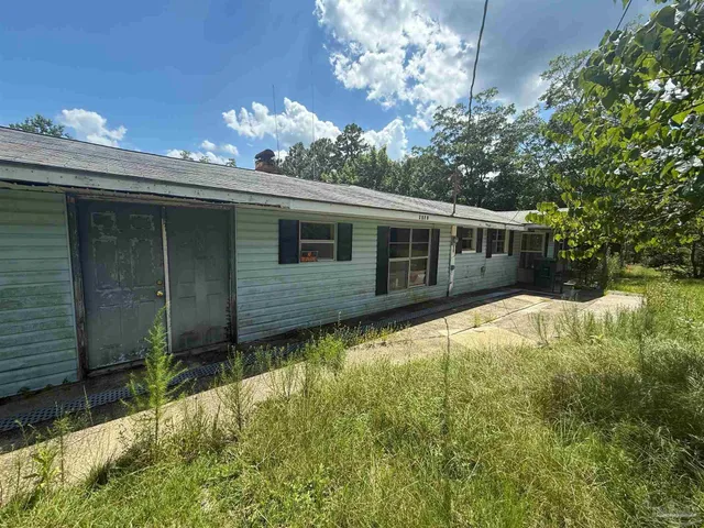 a house is sitting in middle of green field