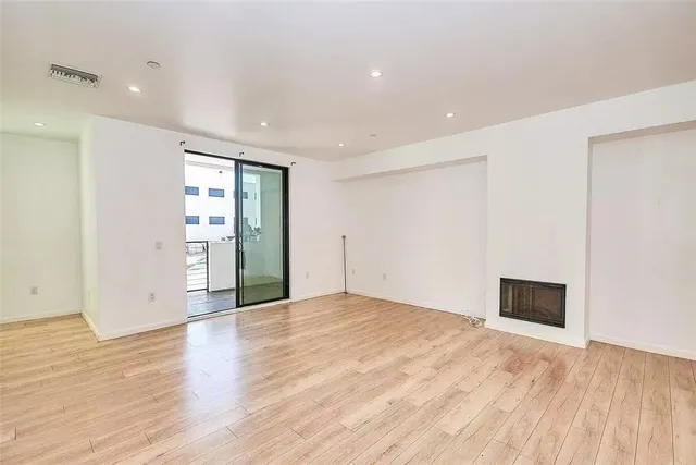 a view of an empty room with wooden floor and closet