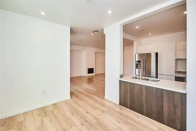 a large kitchen with stainless steel appliances a large counter top a sink and a refrigerator