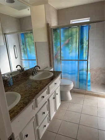 a bathroom with a granite countertop sink a toilet a mirror and shower