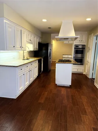 a large kitchen with a wooden floor and stainless steel appliances