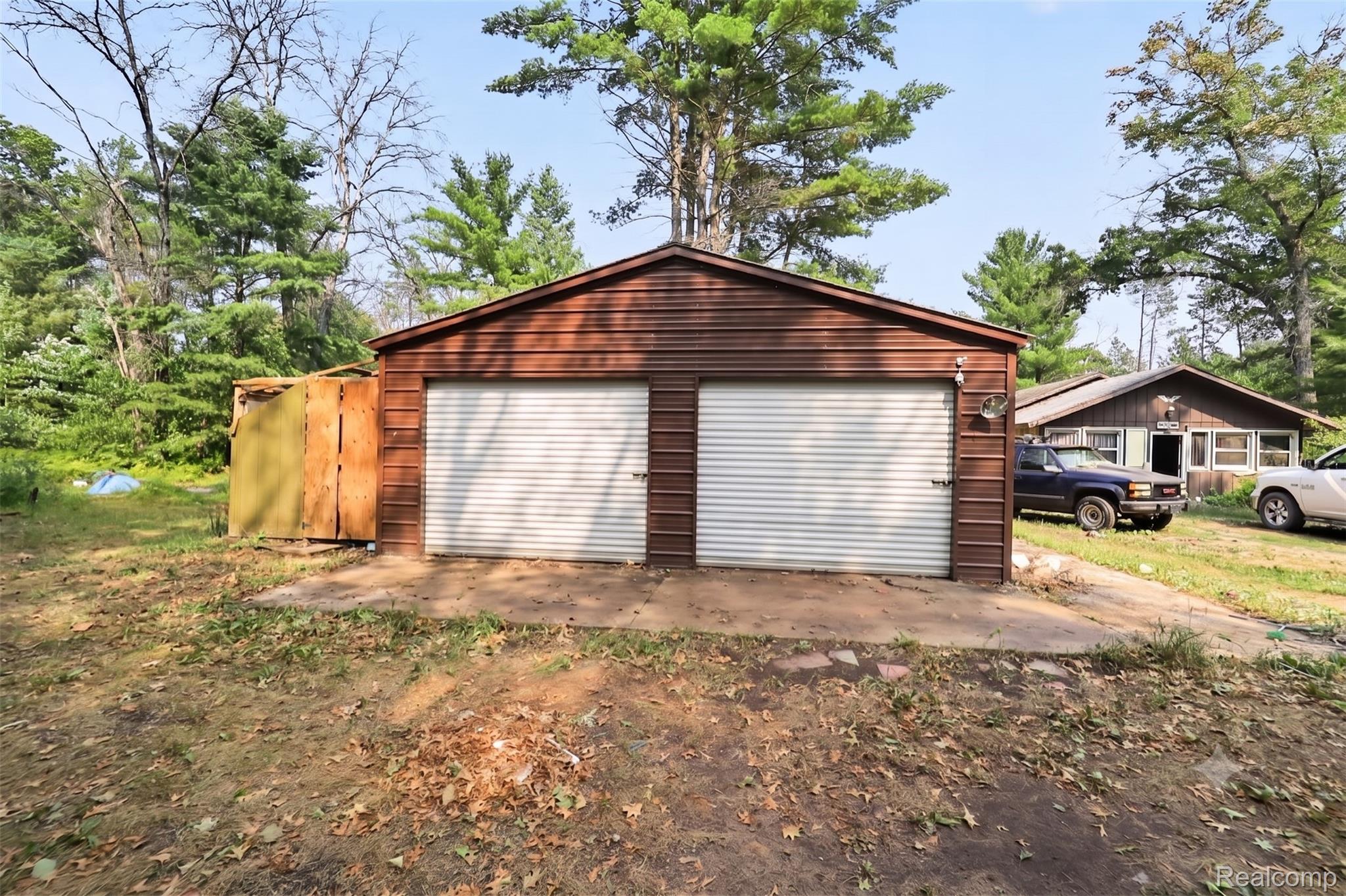 2166 South Forman Road Baldwin, MI 49304 - Photo 24 of 31 Two-car detached garage with brown horizontal siding, concrete pad, and two overhead doors