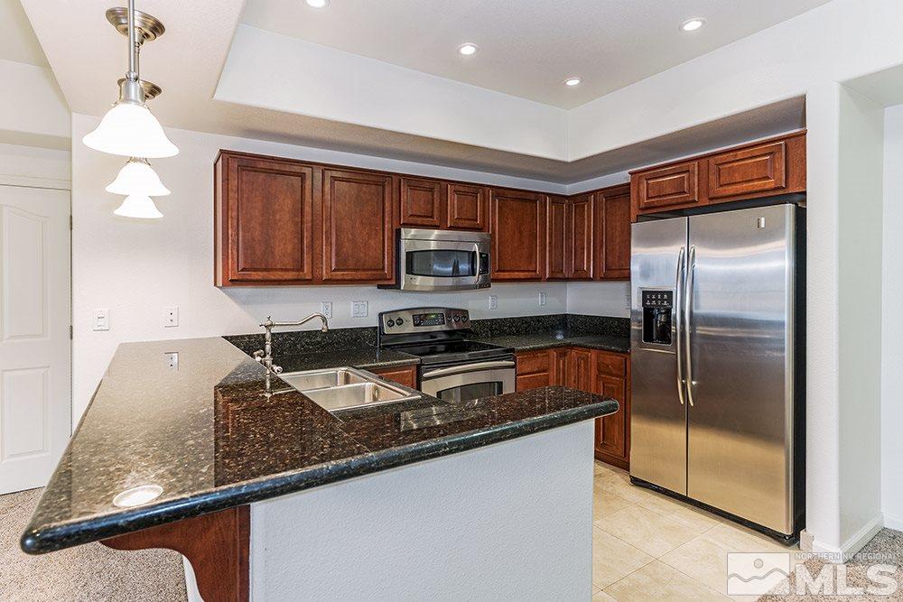 a kitchen with granite countertop a refrigerator a stove a sink and a counter top space