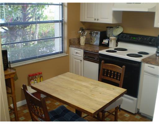 7970 Eastlake Drive, Unit 15A Boca Raton, FL 33433 - Photo 4 of 12 a kitchen with a stove a table and chairs