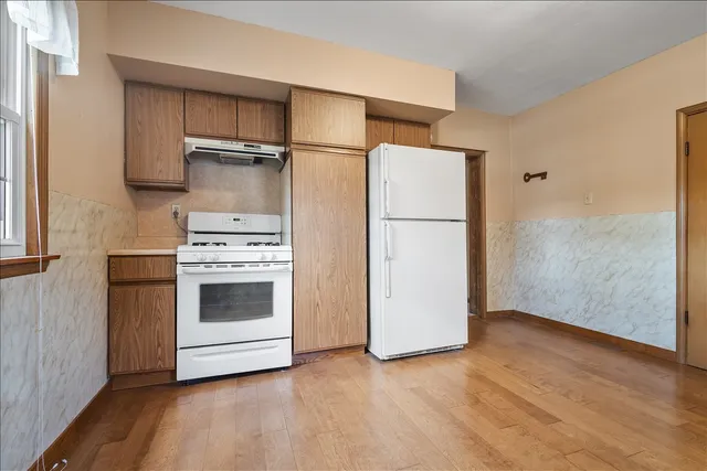 a kitchen with a stove a refrigerator and a wooden floor