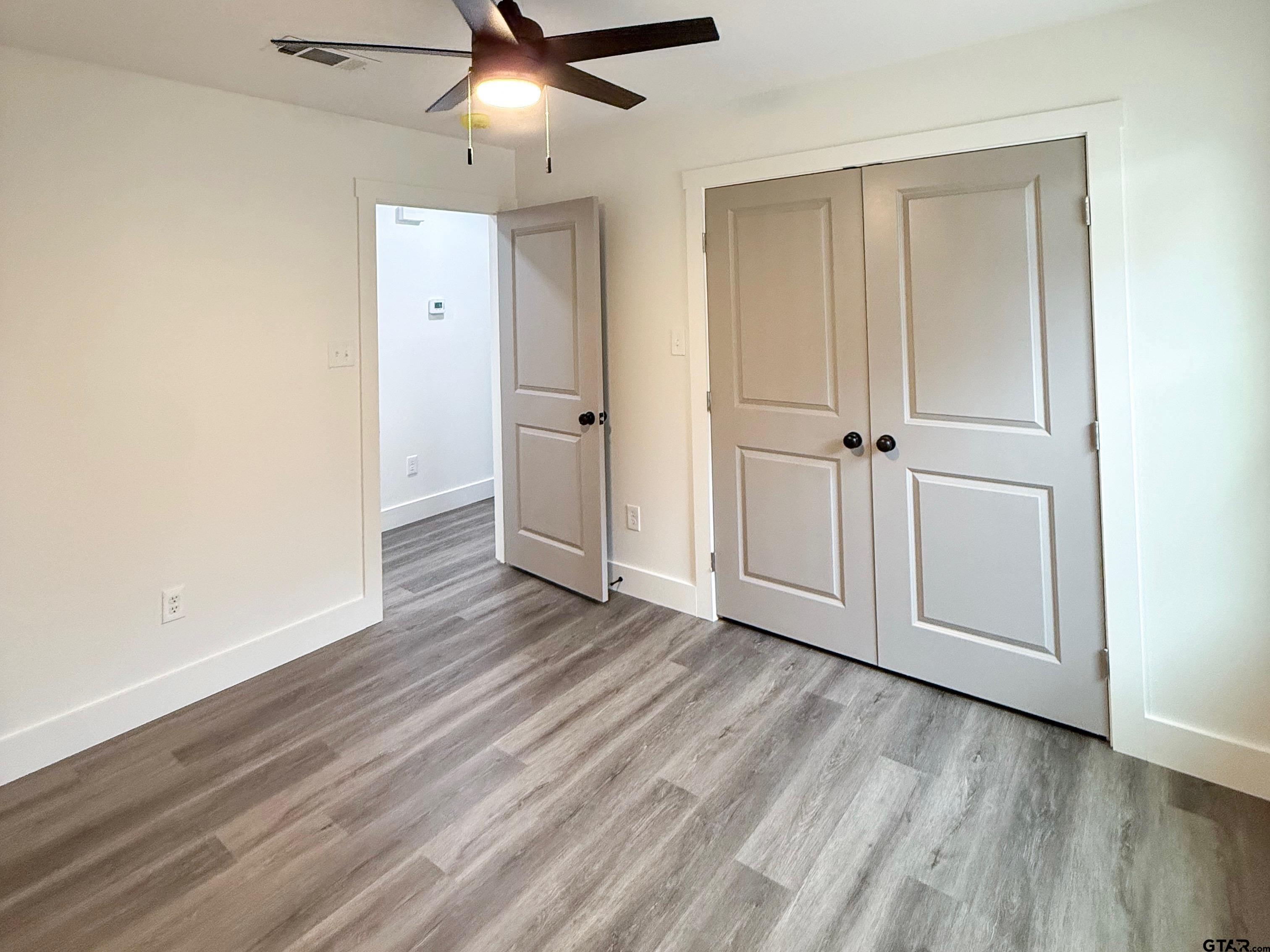 412 Garver Street Pittsburg, TX 75686 - Photo 11 of 11 an empty room with wooden floor cabinet and windows