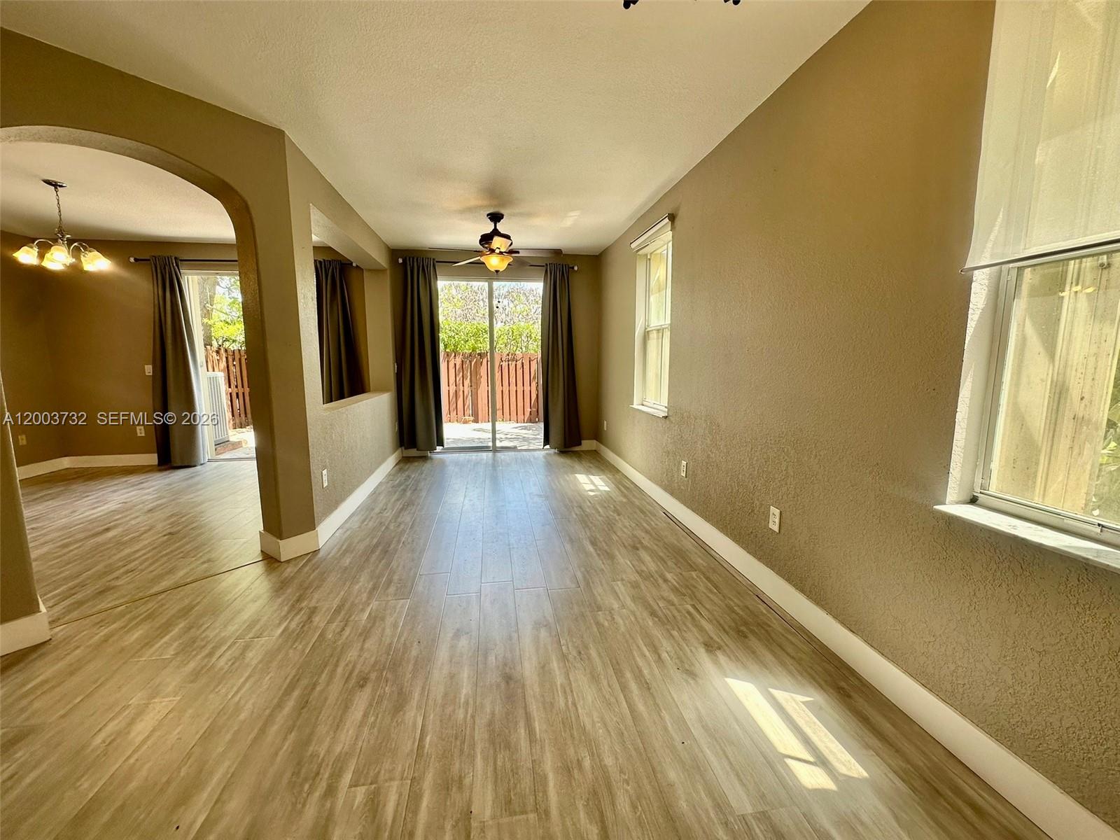 a view of a big room with wooden floor and windows