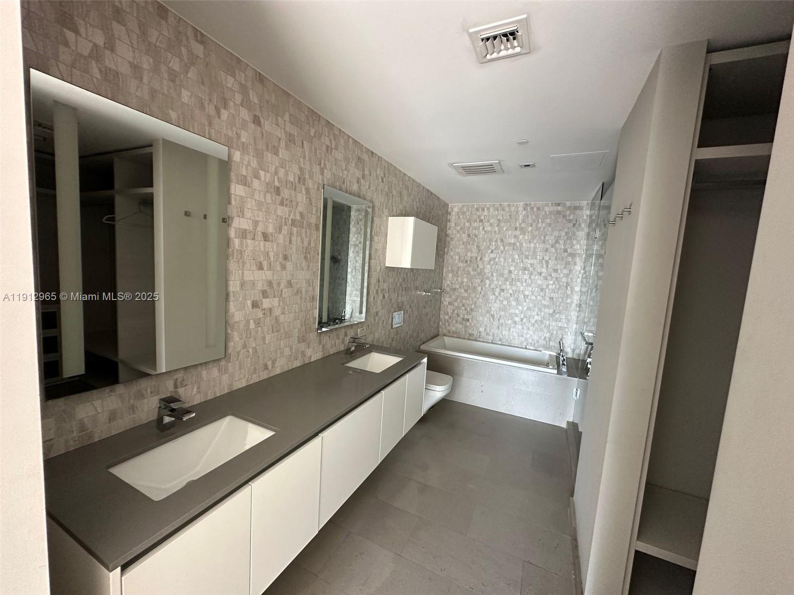 68 Southeast 6th Street, Unit 2205 Miami, FL 33131 - Photo 28 of 28 a spacious bathroom with a bathtub sink and mirror