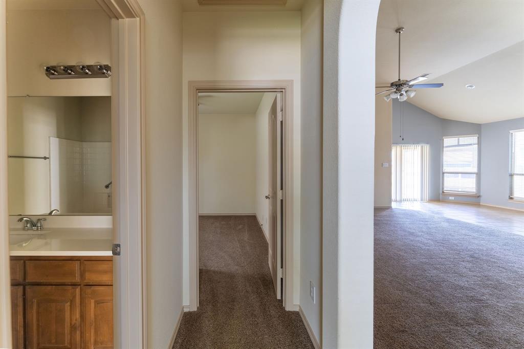11156 Hawks Landing Road Fort Worth, TX 76052 - Photo 9 of 30 Hallway featuring textured carpet flooring, leading to a bathroom with a wood-finish vanity and a separate room