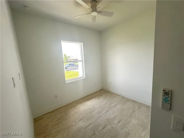an empty room with a window and a fan