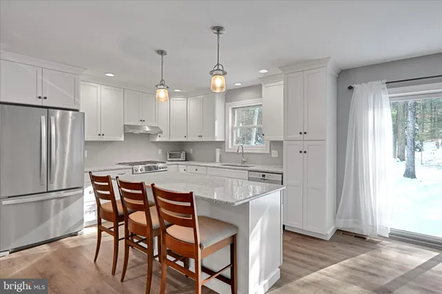 a kitchen with stainless steel appliances granite countertop a stove top oven a refrigerator a sink dishwasher with a dining table and chairs with wooden floor