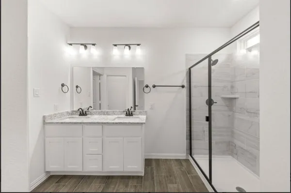 a bathroom with a granite countertop sink a mirror a vanity and shower