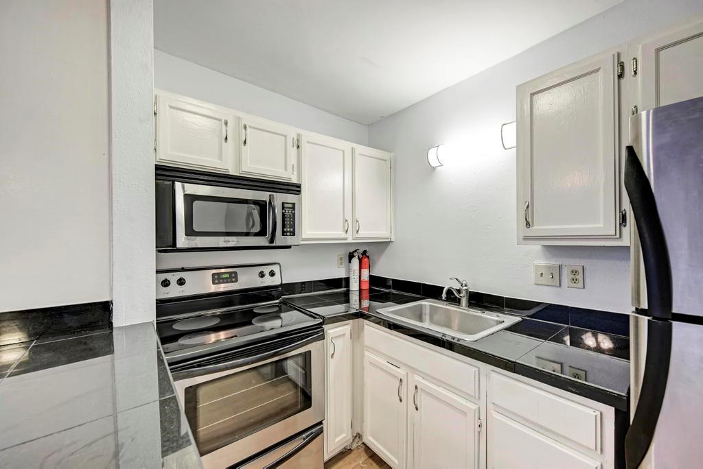 1000 West 26th Street, Unit 113 Austin, TX 78705 - Photo 5 of 10 a kitchen with white cabinets stainless steel appliances and sink