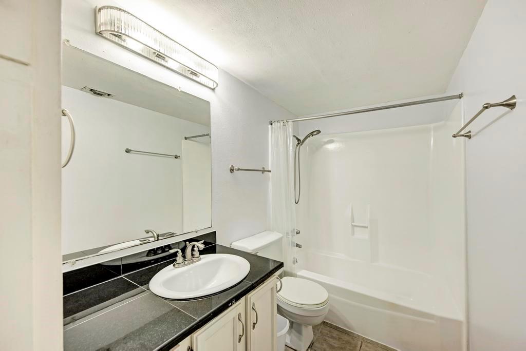 1000 West 26th Street, Unit 113 Austin, TX 78705 - Photo 8 of 10 a bathroom with a granite countertop sink toilet a mirror and shower