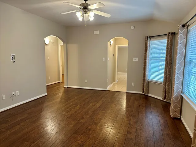 a view of an empty room with wooden floor and a window