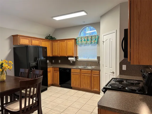 a kitchen with granite countertop a refrigerator stove top oven and sink