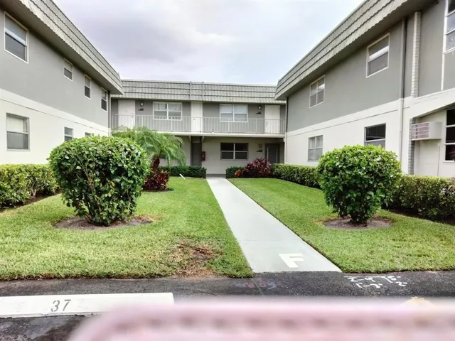 a front view of a house with a yard and potted plants