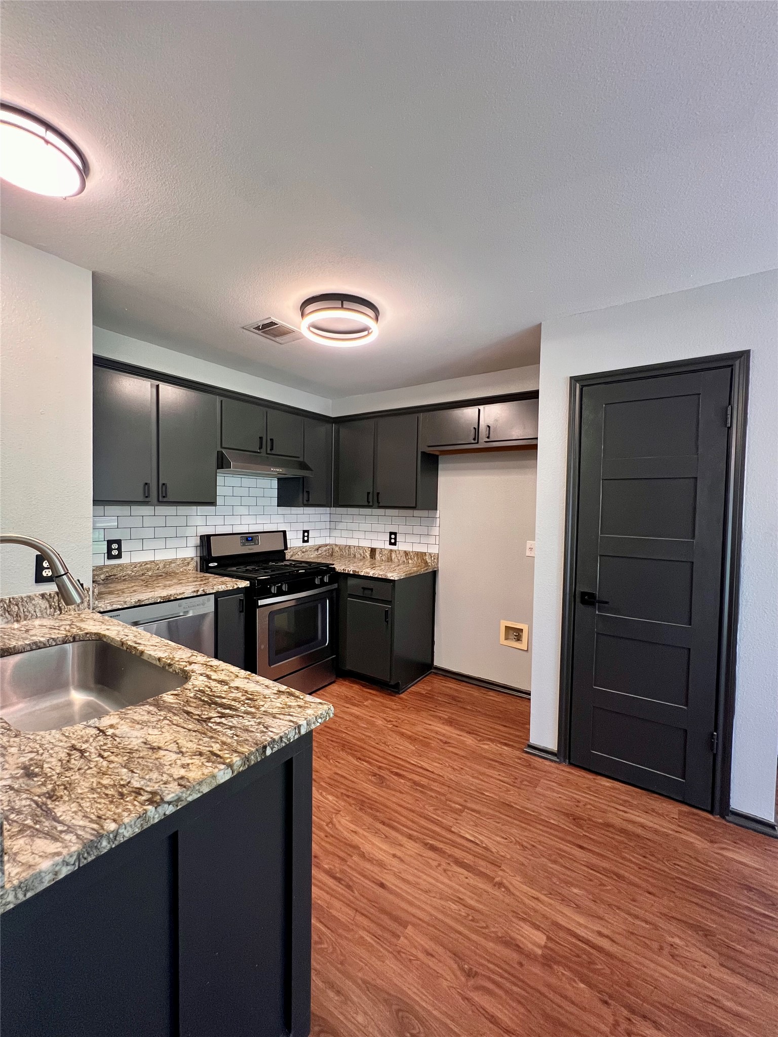 5404 China Berry Road Austin, TX 78744 - Photo 5 of 20 Modern kitchen features granite counters, stainless steel appliances, and rich wood flooring.