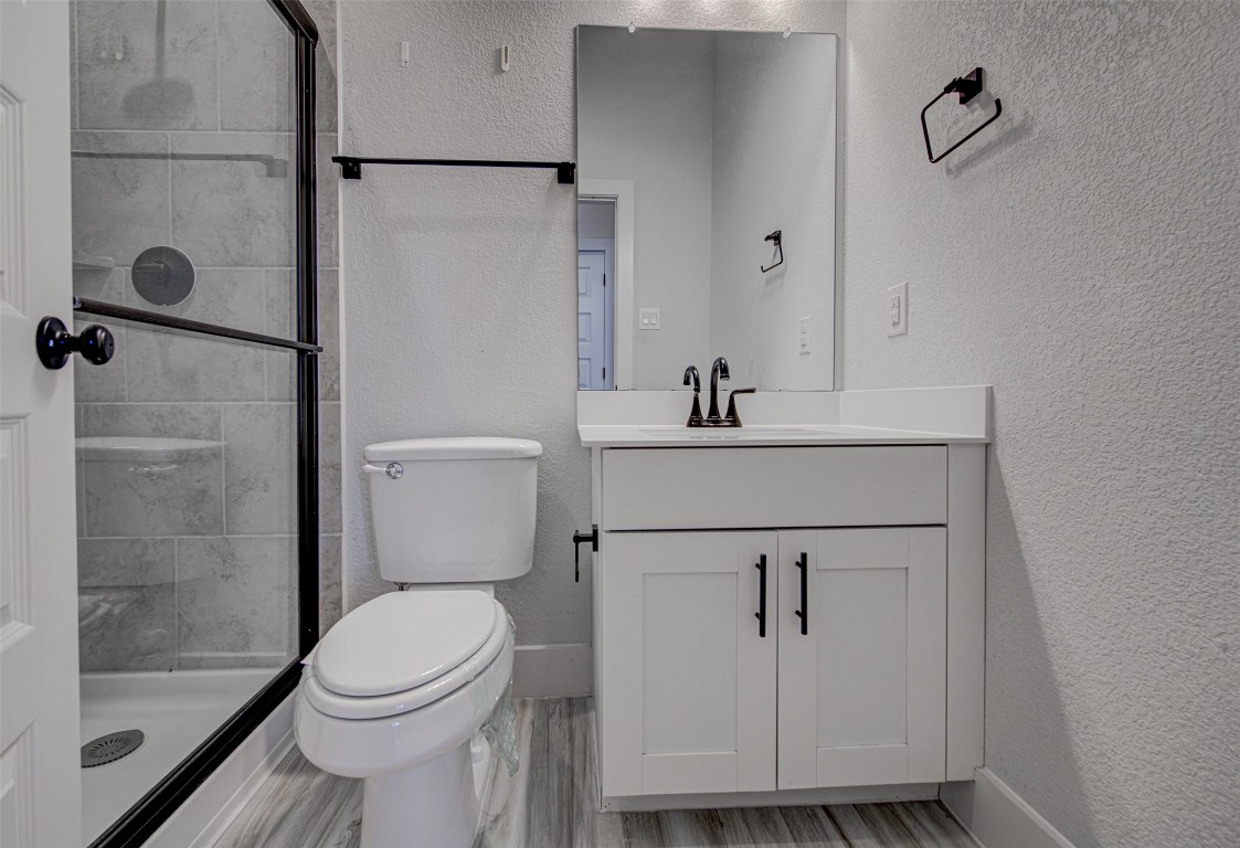 822 Wild Pecan Loop Buda, TX 78610 - Photo 11 of 33 Bathroom with a textured wall, vanity, a stall shower, and light wood-style floors