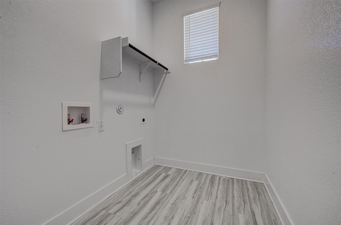 822 Wild Pecan Loop Buda, TX 78610 - Photo 12 of 33 Laundry area featuring a textured wall, gas dryer hookup, washer hookup, hookup for an electric dryer, and light wood-type flooring