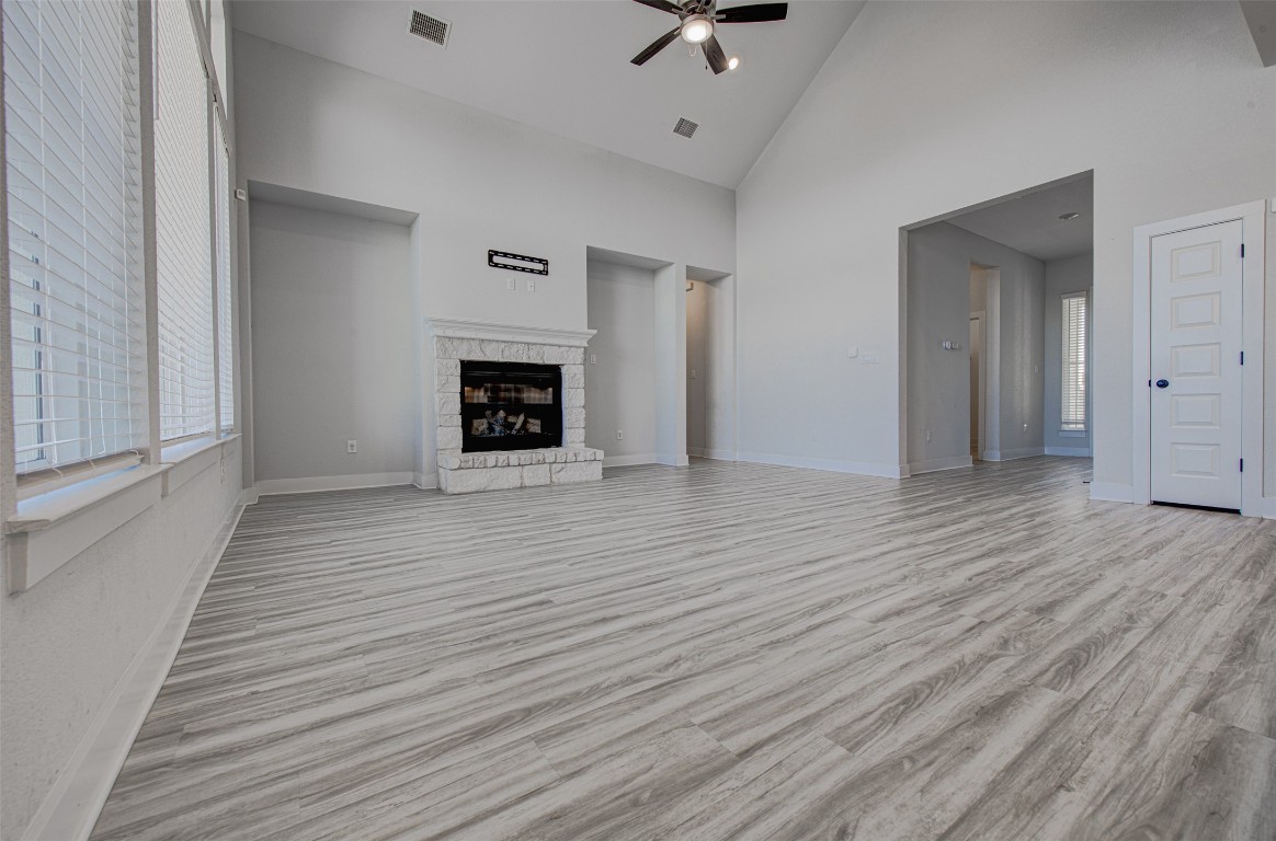 822 Wild Pecan Loop Buda, TX 78610 - Photo 15 of 33 Unfurnished living room featuring high vaulted ceiling, a fireplace, light wood-style flooring, and a ceiling fan