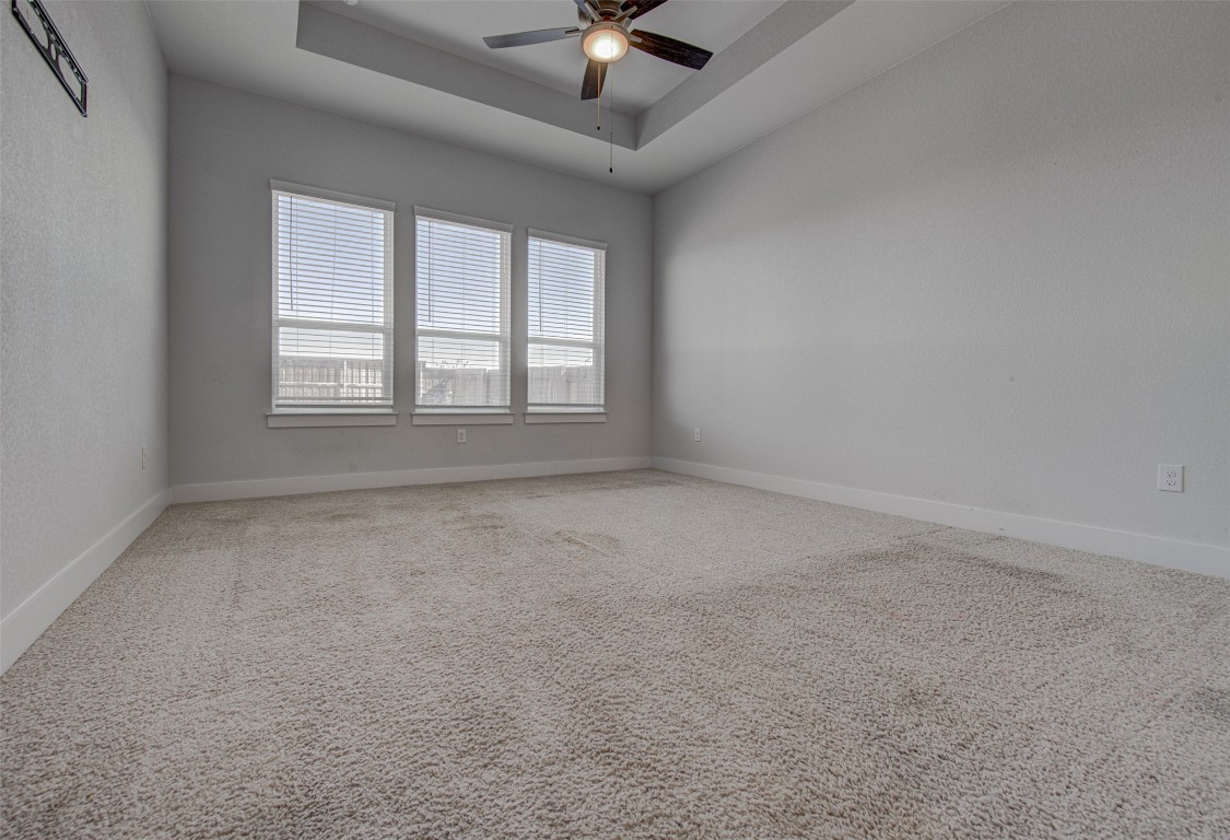 822 Wild Pecan Loop Buda, TX 78610 - Photo 17 of 33 Carpeted spare room featuring a tray ceiling and ceiling fan