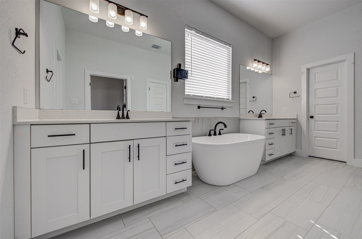 822 Wild Pecan Loop Buda, TX 78610 - Photo 19 of 33 Bathroom featuring two vanities and a freestanding tub